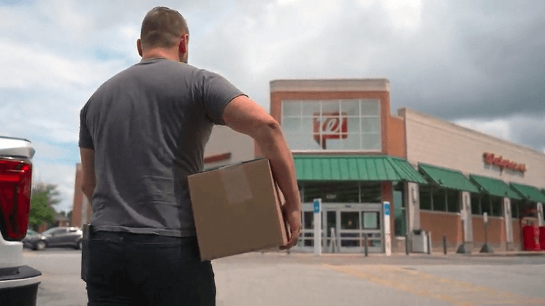 Guy carrying package into FedEx drop-off location